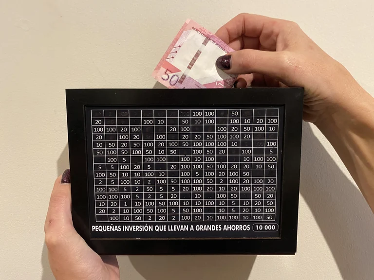 Persona colocando dinero en una alcancía personalizada